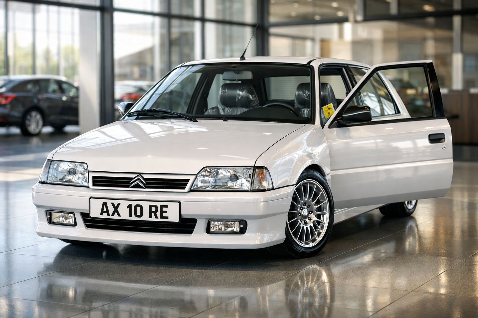 Carro Citroën AX branco estacionado em piso interior, com porta dianteira direita aberta.